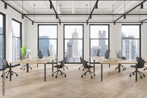 Modern coworking interior with pc monitors on tables  panoramic window
