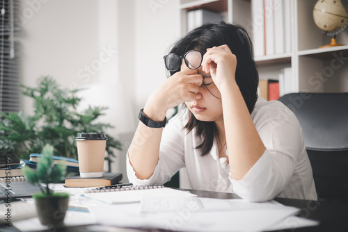 Stressed businesswoman, dealing with the pressures of work and the weight of depression, finds herself struggling in the office, feeling sleepy and overwhelmed by the demands of her job.