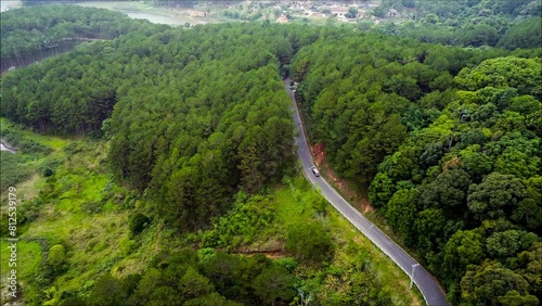 Aerial, top down, drone shot, following a car, on a asphalt road, in the forest, on a sunny, autumn day, on the countryside of Uusimaa, Finland photo