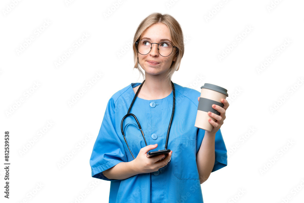 Young nurse English woman over isolated background holding coffee to take away and a mobile while thinking something