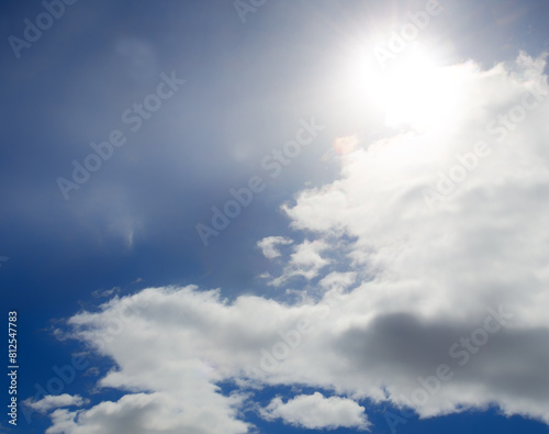 Bright light of the sun on a dark blue sky among the clouds. Dramatic view of the sun.