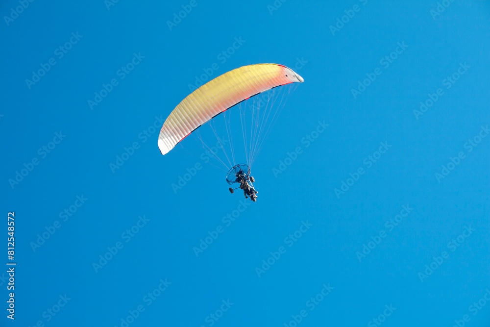 Paraglider with motor over the zenith of the observer and with blue sky in the background Paraglider with motor over the zenith of the observer and with blue sky in the background
