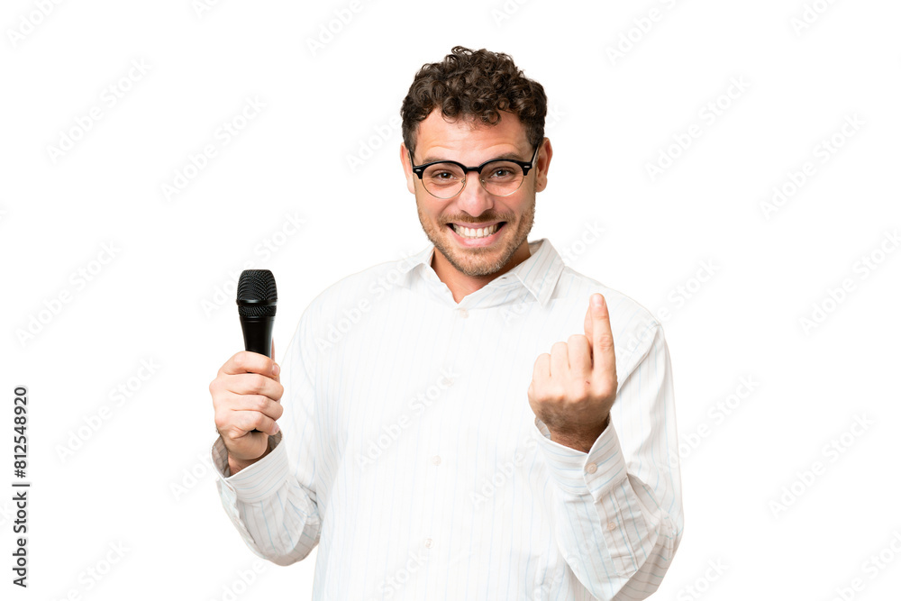 Brazilian man picking up a microphone over isolated chroma key background making money gesture Brazilian man picking up a microphone over isolated chroma key background making money gesture