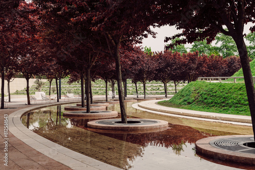 Park with modern design and trees with red foliage and an artificial pond