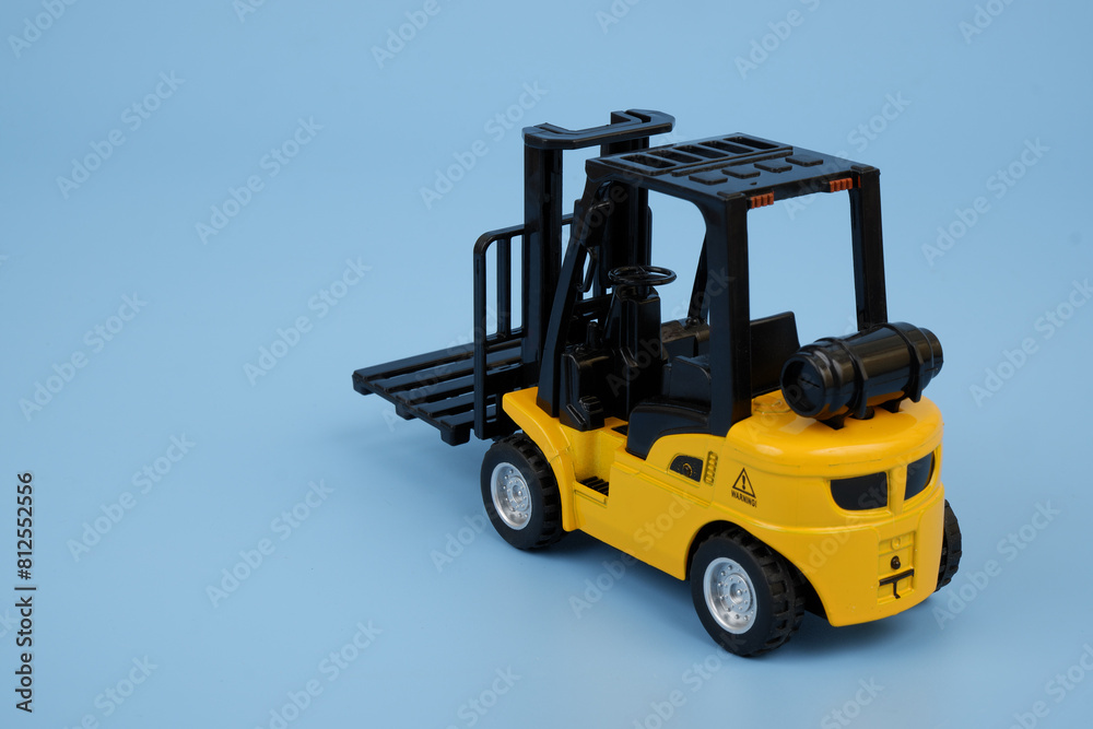 Yellow forklift truck model on blue background. Copy space for text.