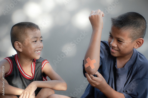 Two boys sitting and smiling with wound on elbow from accident on blur background and bokeh,Children smile and charming ,young Asian two boys,Children and accident,playing outdoor,isolated background. photo
