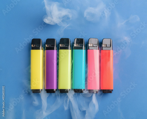 Set of colorful disposable electronic cigarettes on a blue background. The concept of modern smoking. Top view. smoke in the background. High quality photo