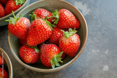 Ripe strawberries in a rustic bowl on a dark textured surface  perfect for food themes