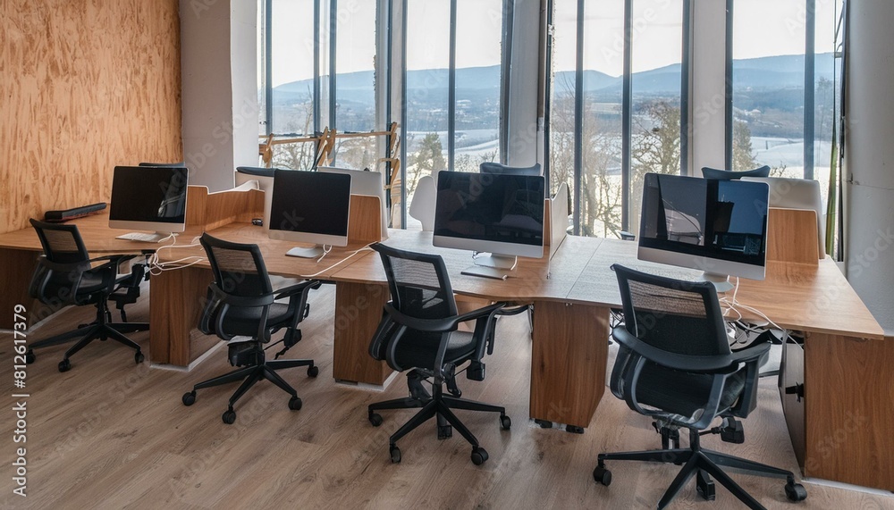 Wooden coworking interior with pc computers on desks in row, panoramic window Wooden coworking interior with pc computers on desks in row, panoramic window