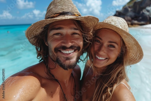 A cheerful couple in straw hats taking a selfie with a clear blue ocean backdrop, showcasing a happy vacation moment