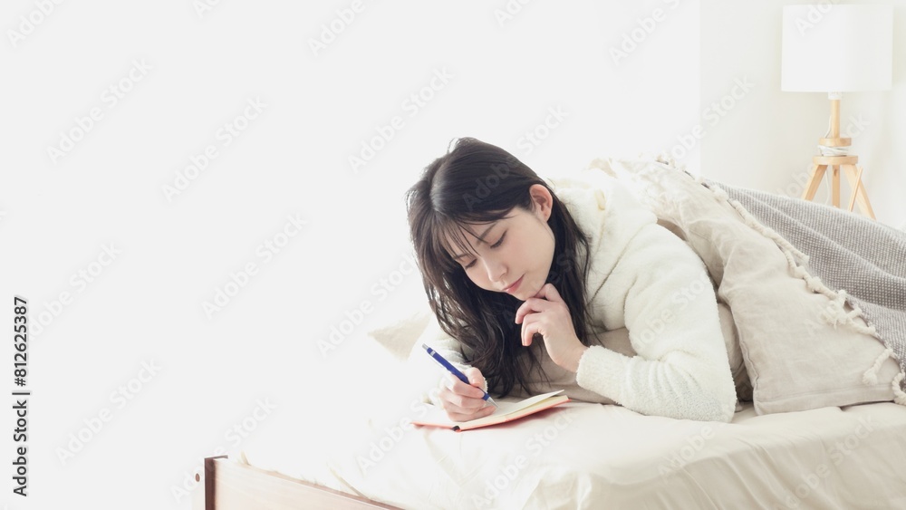 寝ながらメモをとるアジア人女性