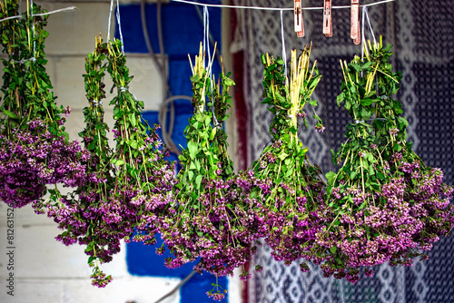 Purple blossoms suspended upside down for drying; their vibrant color against the muted background evokes a sense of natural beauty.