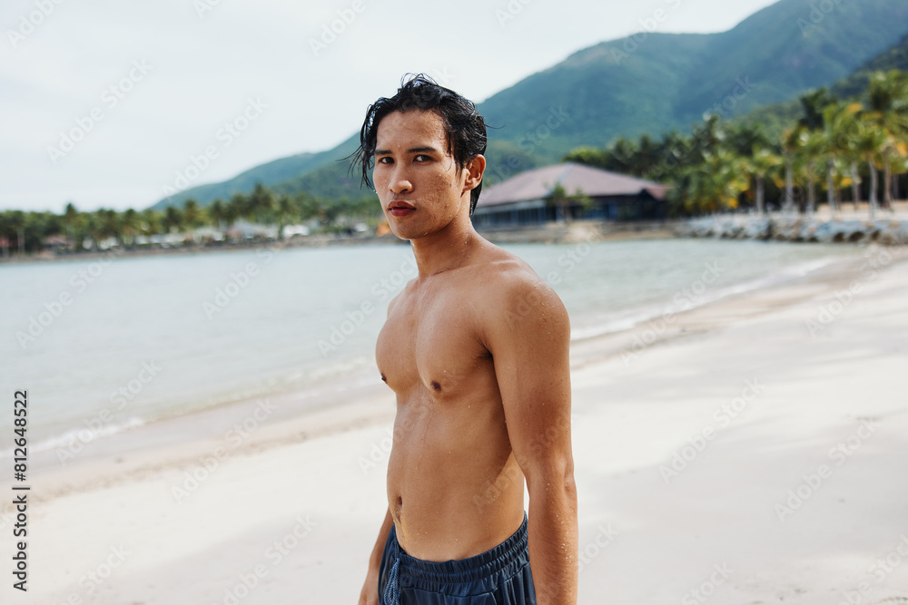 Smiling Asian Man Enjoying Tropical Beach Vacation with Muscular Torso Smiling Asian Man Enjoying Tropical Beach Vacation with Muscular Torso
