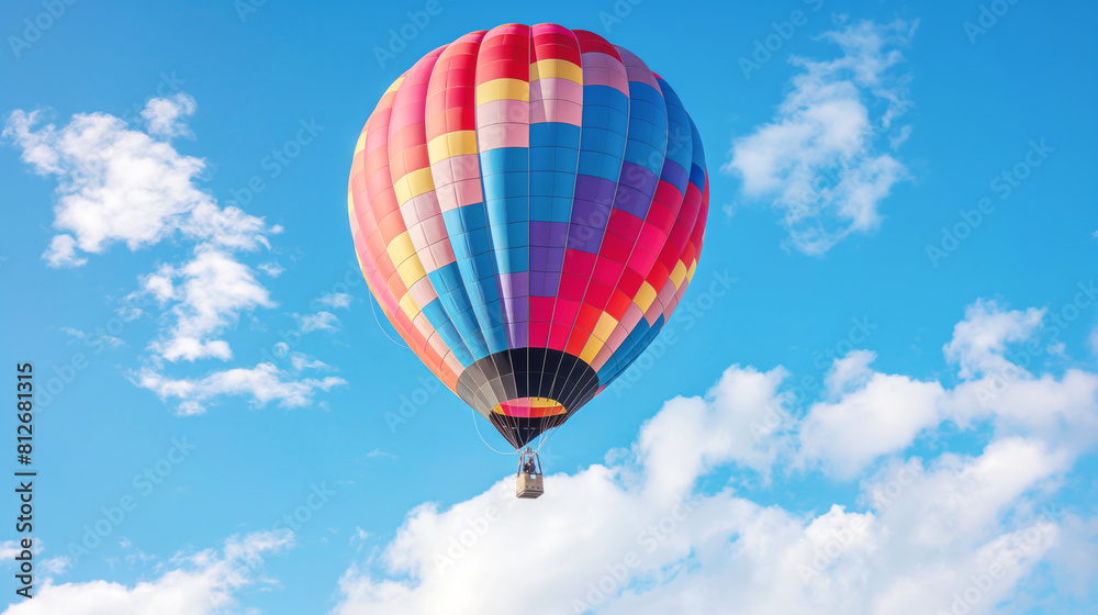 Naklejka premium Colorful hot air balloon soaring through clear blue sky with fluffy clouds offering serene and adventurous aerial journey. Brightly striped pattern enhances cheerful uplifting ambiance