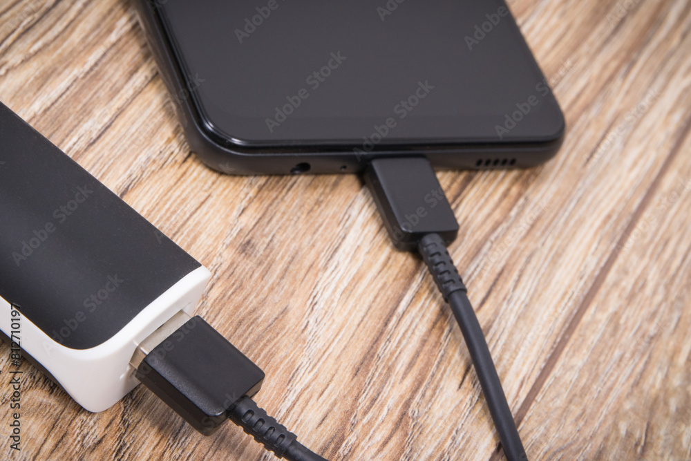External powerbank using to charge empty battery of black smartphone External powerbank using to charge empty battery of black smartphone