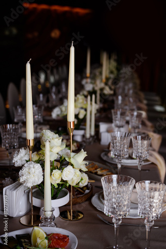 White candles in candelabra and white flowers on the wedding table decoration. 