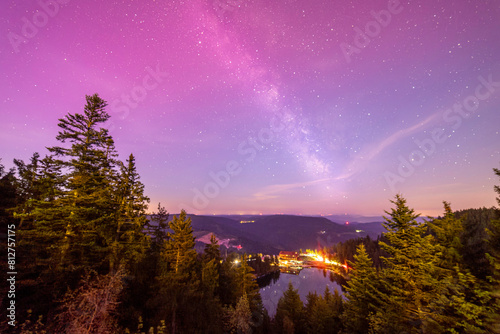 Milky way above Mummelsee in black forest in germany from hornisgrinde with slight red northern lights at top