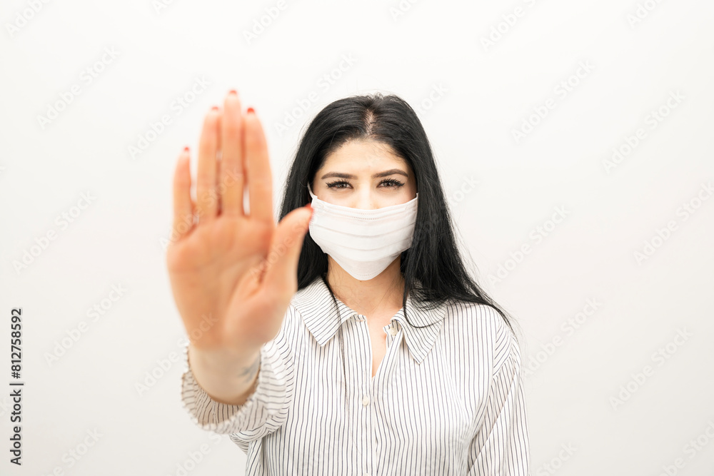 Young woman with surgical mask on face against SARS-CoV-2. woman wearing health mask showing stop sign Young woman with surgical mask on face against SARS-CoV-2. woman wearing health mask showing stop sign