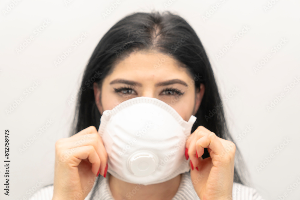 Young woman with surgical mask on face against SARS-CoV-2. COVID-19 Pandemic Coronavirus Young girl in white room wearing face mask Young woman with surgical mask on face against SARS-CoV-2. COVID-19 Pandemic Coronavirus Young girl in white room wearing face mask
