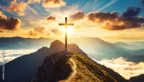 holy cross on top of mountain at sunset or sunrise symbolizing the death and resurrection of jesus christ hill is shrouded in light and clouds horizontal background religion christianism concept photo