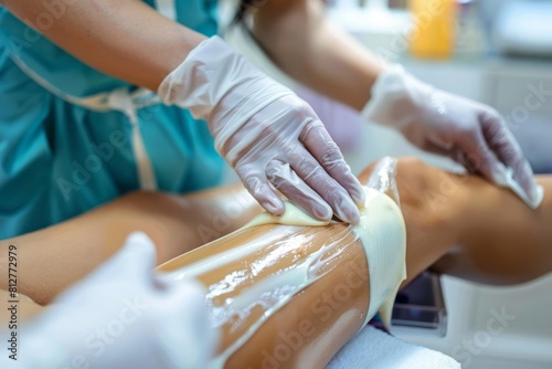 A beautician wearing gloves smoothing wax on a client leg with an emphasis on hygiene and care