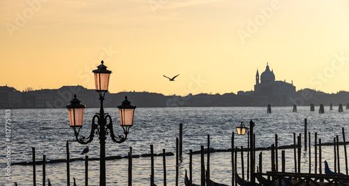 Beautiful view of silhouettes of vintage street light, a seagull and Il Redentore church at sunset in Venice; Italy photo