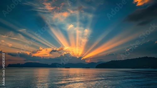 Majestic sunset over a tranquil sea with crepuscular rays piercing through clouds, silhouette of distant islands. photo