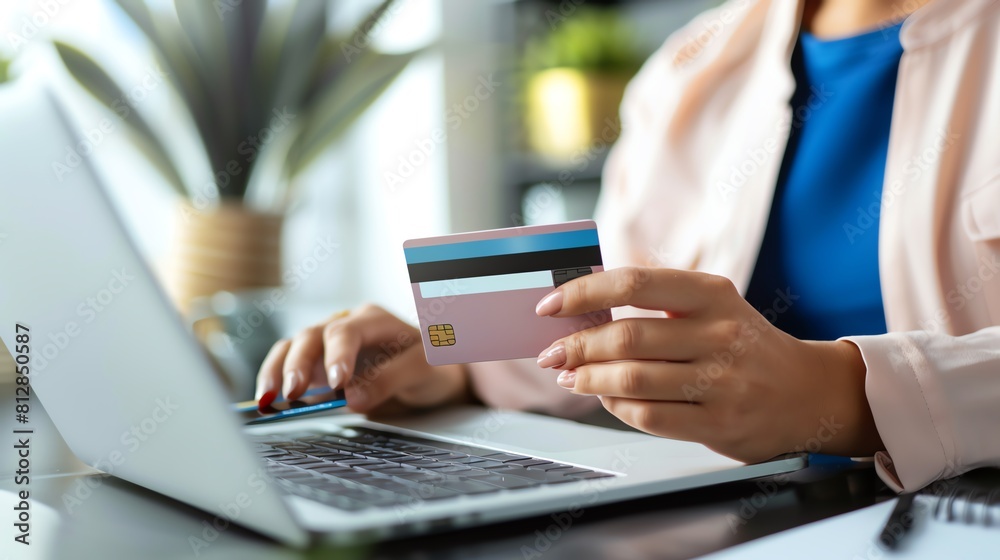 A woman in a pink blazer is holding a credit card and using a laptop. She is shopping online and is about to make a purchase. A woman in a pink blazer is holding a credit card and using a laptop. She is shopping online and is about to make a purchase.