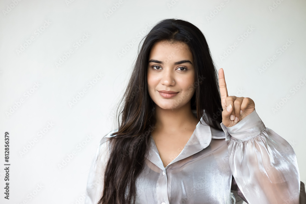 Happy, smiling, friendly south asian woman in pointing up 1 finger, concept image for number one, winner, one point Happy, smiling, friendly south asian woman in pointing up 1 finger, concept image for number one, winner, one point