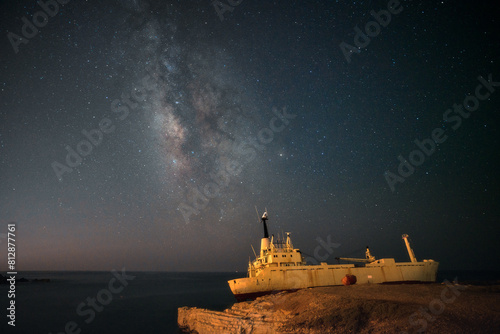 The wrecked ship under night sky with milky way