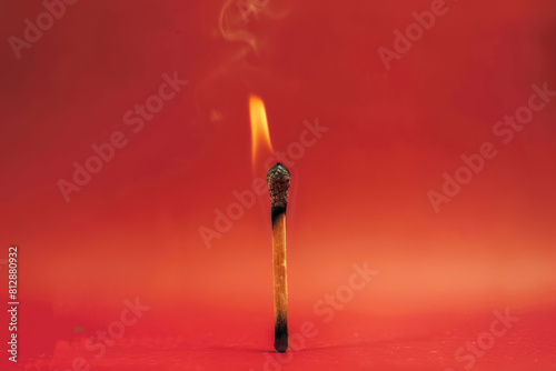 conceptual image of a burned out matchstick on a fading red background