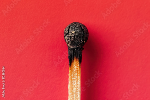 close up of a burnt matchstick head against a vibrant red background