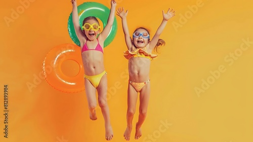 Two funny little girls sisters in swimsuits and swimming goggles jumping up in air with inflatable swimming ring and ball in hands on orange studio background excited and ready for sum   Generative AI