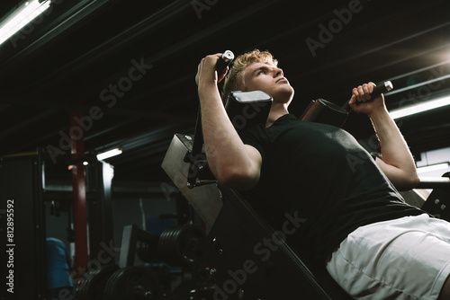 Low angle shot of a male athlete training at the gym, using hack squat machine