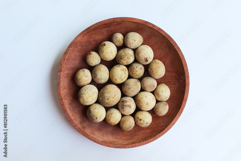 Fruit of Lansium domesticum var duku, known as duku, or langsat, or lanzones, on wooden plate, isolated on white background, flat lay or top view Fruit of Lansium domesticum var duku, known as duku, or langsat, or lanzones, on wooden plate, isolated on white background, flat lay or top view
