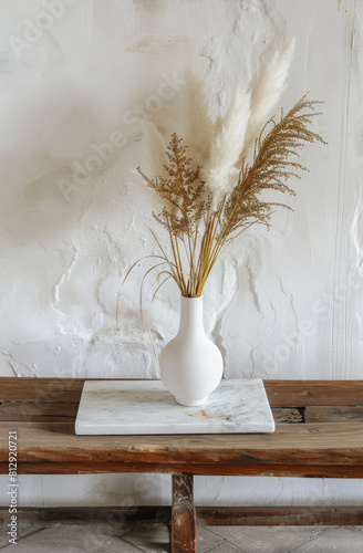 Modern white ceramic vase with dry Lagurus ovatus grass and marble tray on vintage wooden bench