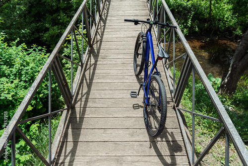 Blue mountain bike parked on a wooden bridge over a river. Cycling background.