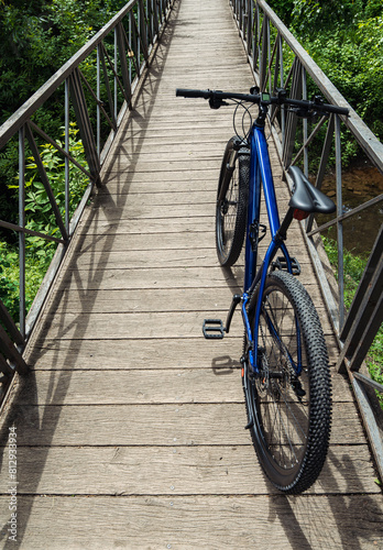 Blue mountain bike parked on a wooden bridge over a river. Cycling vertical background.