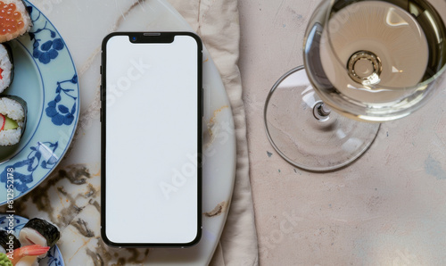 White Screen Smartphone Mockup with Sushi Dinner on Natural Stone and Marble Table: Top View of Blank Screen Mobile Phone with Sushi, Chopsticks and Glass of Wine