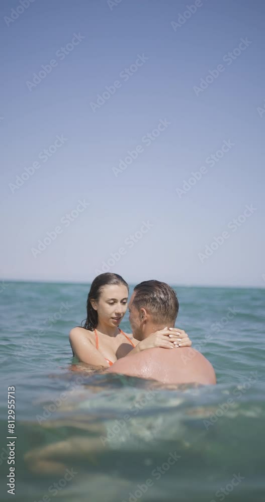 Couple having good time at sea. Boyfriend and girlfriend hugging in the water. Summer fun concept. Vertical video recorded on cinema camera at 120fps. Couple having good time at sea. Boyfriend and girlfriend hugging in the water. Summer fun concept. Vertical video recorded on cinema camera at 120fps.