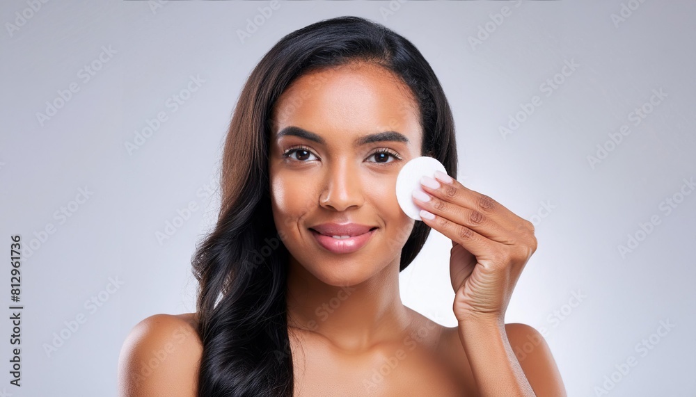 beautiful young woman using a cotton pad on a light isolated background. Concept of clean skin, facial care and natural cosmetics 