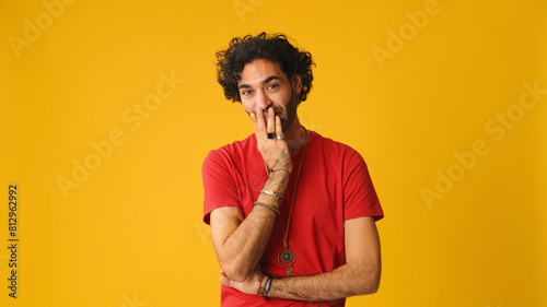 Upset dissatisfied man with curly hair wearing red T-shirt, showing disagreement looking at camera isolated on yellow background in studio © Andrii Nekrasov