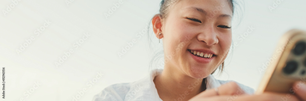 Fototapeta premium Closeup, Smiling young woman using mobile phone on seascape background, Panorama