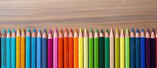 A copy space image of colored pencils arranged on a wooden table for a presentation