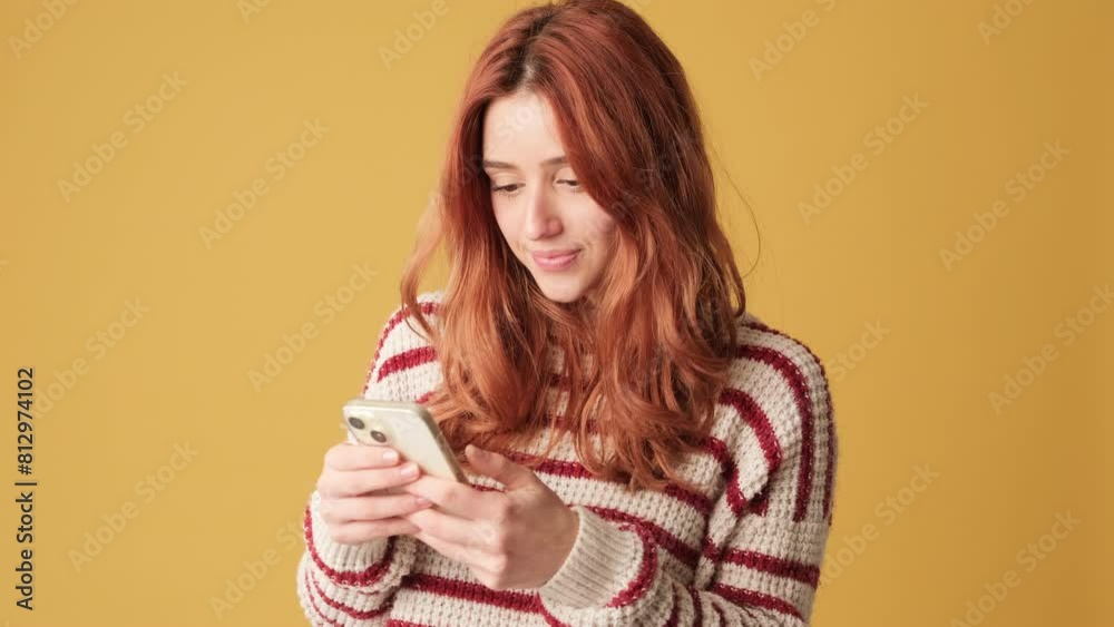Girl with mobile phone in hands celebrates victory on yellow background Girl with mobile phone in hands celebrates victory on yellow background