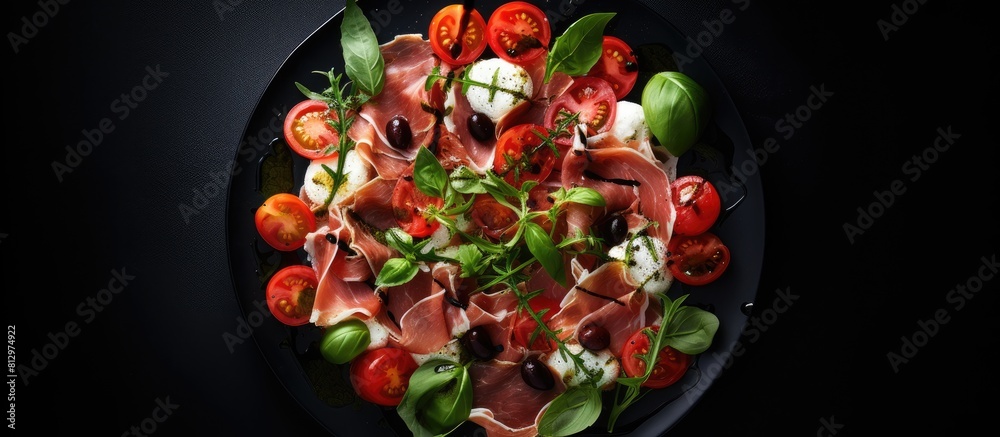 Top view copy space image showcasing a delicious arrangement of prosciutto salad consisting of mozzarella cherry tomatoes capers and spinach The salad is presented on a dark plate placed against a da