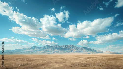 A vast landscape with a distant mountain range under a cloudfilled blue sky photo