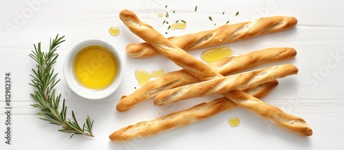 A flat lay image showcasing grissini breadsticks accompanied by olive oil on a plain white background allowing ample space for text photo
