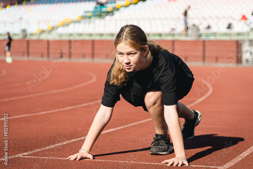 Fotografie Athlete teenager preparing before jogging running, stretching legs before workout training outdoors on stadium in the morning