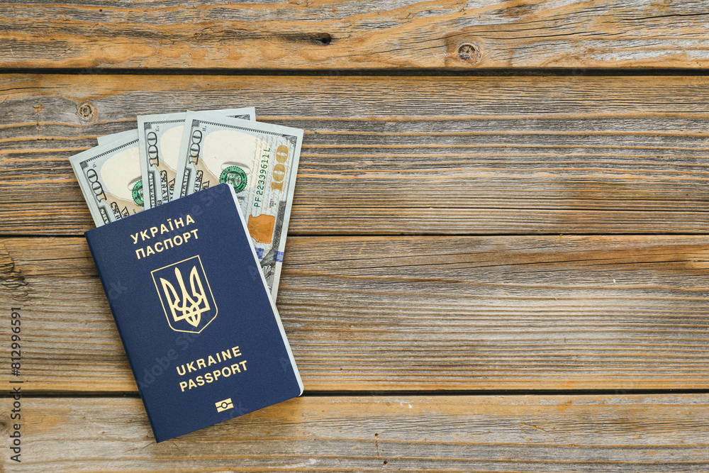 Biometric Ukrainian passport and money on a wooden background isolated. Passport of a citizen of Ukraine and dollar bills close-up. Copy space. Biometric Ukrainian passport and money on a wooden background isolated. Passport of a citizen of Ukraine and dollar bills close-up. Copy space.